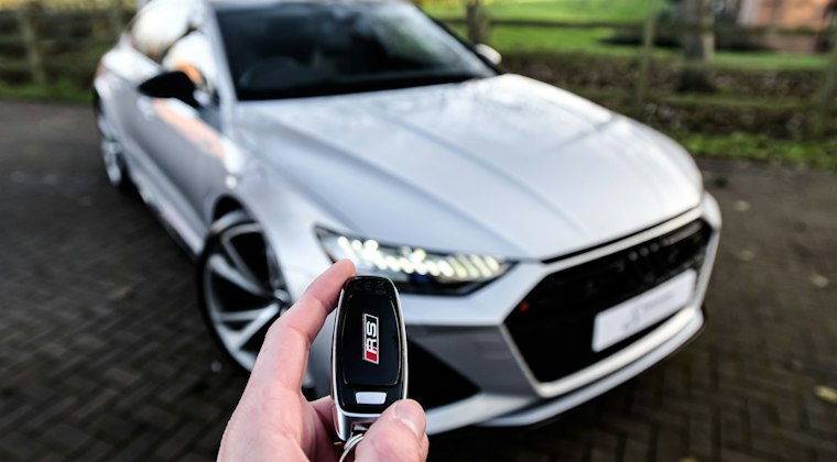 Person holding a car key in front of a silver car